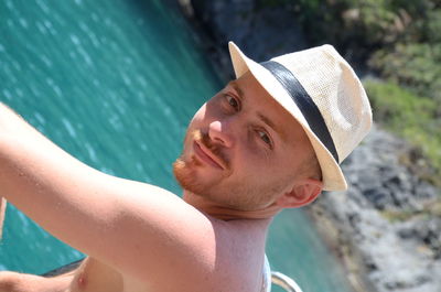 Close-up portrait of man wearing hat against sea