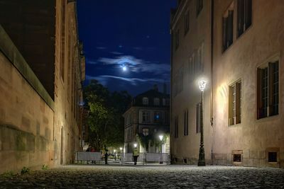Illuminated street light against sky at night