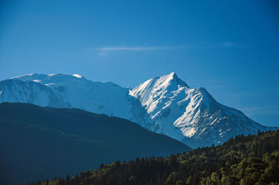 Alpine mountain landscape with forests and blue sky, near saint-gervais-les-bains, france.