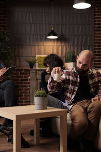 Rear view of woman using mobile phone while sitting at home