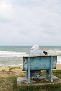 Woman sitting on bench at beach