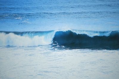 Waves rushing towards shore against sky