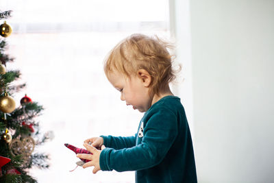 Little baby holding a christmas toy with a christmas tree in his hands. new year and christmas