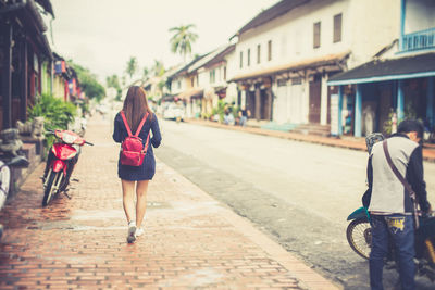 Rear view of woman walking on footpath