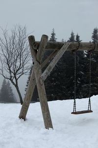 Wooden structure on snow covered landscape against sky