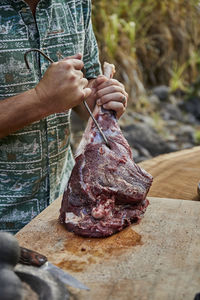 Chef preparing local vension leg for roasting at barbecue