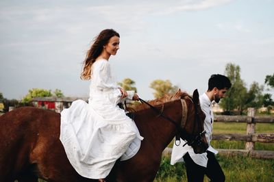 Couple riding horse on field