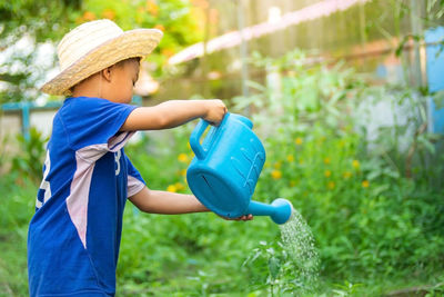 Boy wearing hat against plants in yard