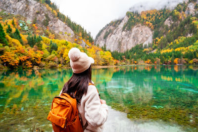 Rear view of woman standing against lake