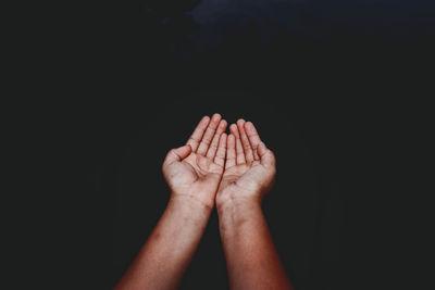 Close-up of hands cupped over black background