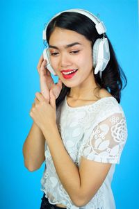 Smiling young woman standing against blue wall