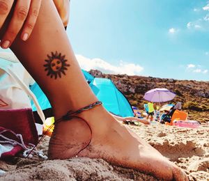 Midsection of woman relaxing on beach against sky