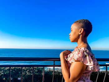 Side view of woman looking at sea against clear sky