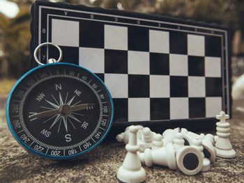 Close-up of navigational compass and chess board on table