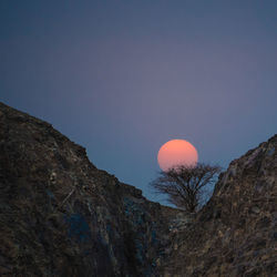 Low angle view of moon over mountain at dusk