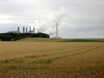 View of field against cloudy sky