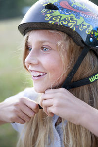 Smiling girl putting on cycling helmet, sweden