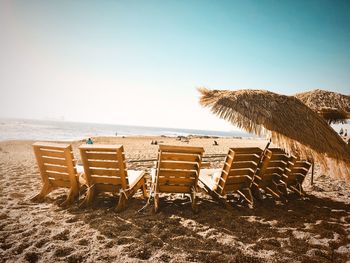 Chairs on beach against clear sky