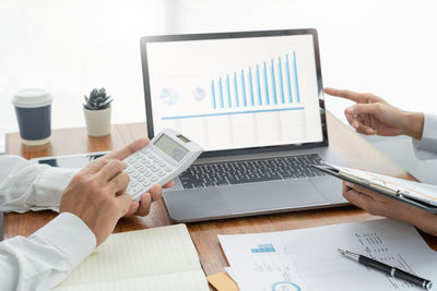 Midsection of businessman and colleague working on table