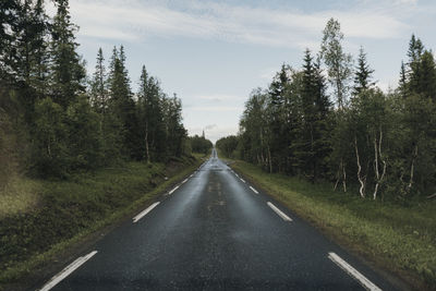 Road amidst trees in forest against sky