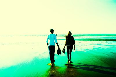 Rear view of friends walking on beach