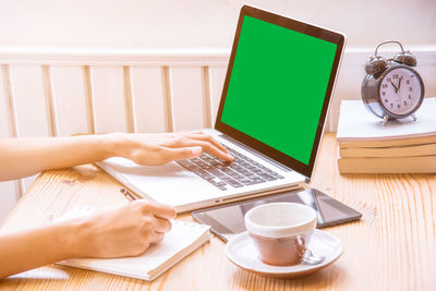 Midsection of woman working with coffee cup on table