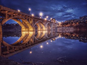 Arch bridge over river against sky at night