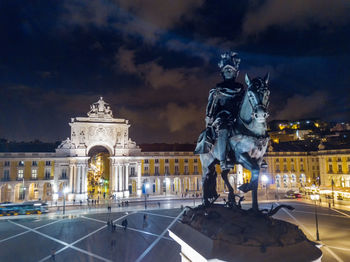 Statue in city against cloudy sky