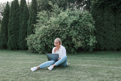 Full length of woman sitting on mobile phone