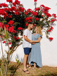 Full length of couple standing by flowering plants