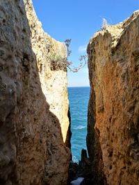 Rock formation by sea against clear sky