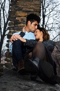 Man kissing girlfriend while sitting at park