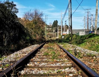 Railroad tracks by trees against sky