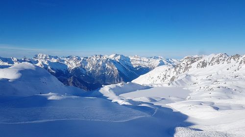 Scenic view of snowcapped mountains against clear blue sky