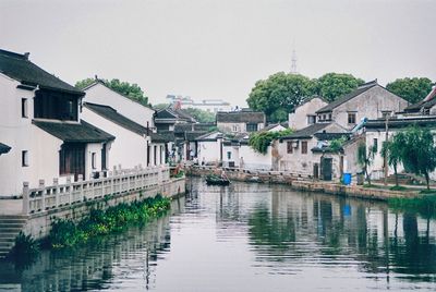 River amidst houses and buildings against sky