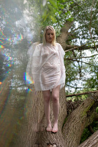 Young woman standing against trees in forest