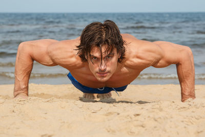 Man practicing push ups at beach