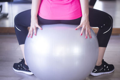 Low section of woman sitting on fitness ball