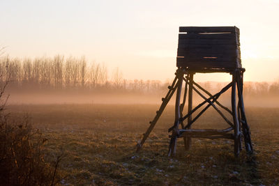 Lookout tower on field against sky during sunset