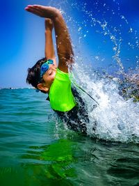 Boy swimming in sea against sky