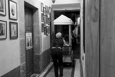 Rear view of man walking on footpath amidst buildings in city