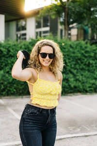 Portrait of young woman wearing sunglasses standing outdoors