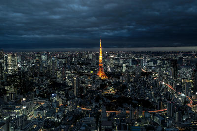 Aerial view of illuminated tokyo tower amidst buildings against cloudy sky