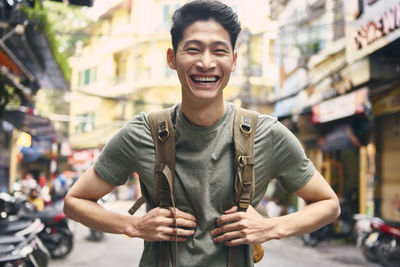 Portrait of smiling young man standing on street in city