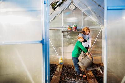 Two young kids taking care of plants in greenhouse