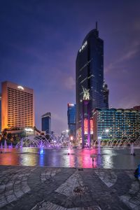 Illuminated city by buildings at night