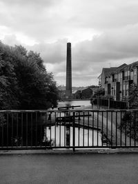 Bridge over river by buildings against sky