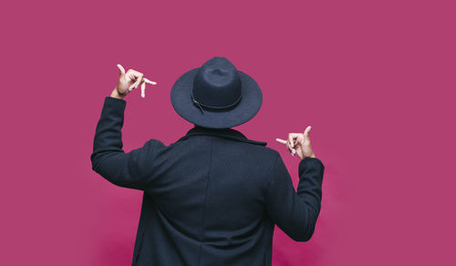 Rear view of man standing against pink background