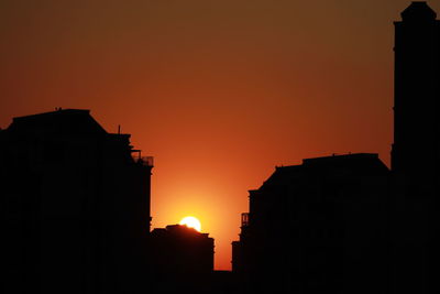 Silhouette buildings against sky during sunset