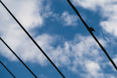 Low angle view of electricity pylon against cloudy sky